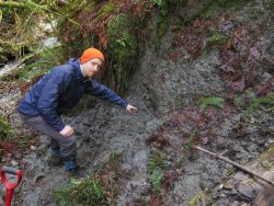 UW graduate student Sean LaHusen pointing to buried debris at an older slide on the north fork of the Stillaguamish River. 