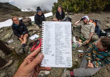 Journal pages list all the species of plants the UW Environmental Studies class has seen by the penultimate day of their backpacking trip in the Olympic National Park backcountry. Here, the group takes a break at Grand Pass.