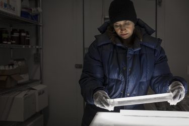 An atmospheric sciences researcher inspects an ice core from Antarctica in the cold room of the UW’s IsoLab.