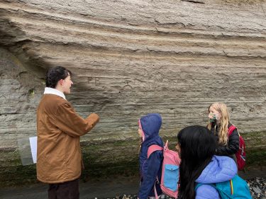 An Earth and Space Sciences graduate student teaches elementary school students about glacial geology at Discovery Park. In the past two years, outreach efforts have reached approximately 1500 K-12 students, including at rural and tribal schools in Washington as well as underserved communities in the Seattle area.