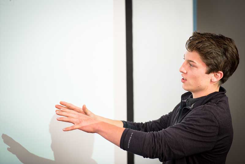 A student gesturing at a whiteboard.