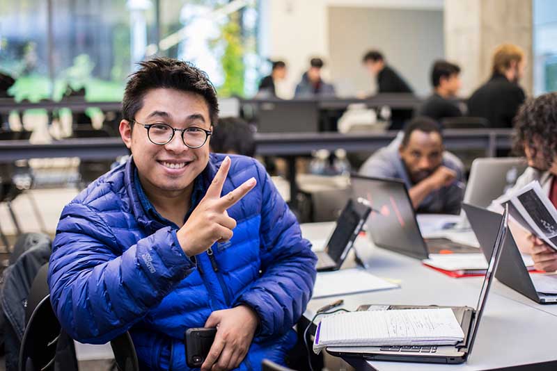 A smiling student flashing a peace sign.